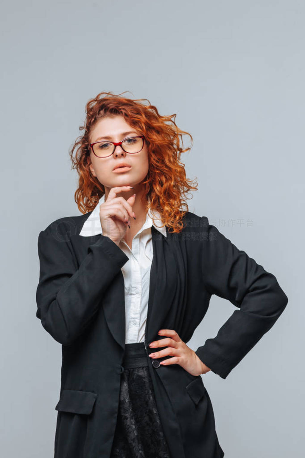 A red-haired woman in a business suit and glasses