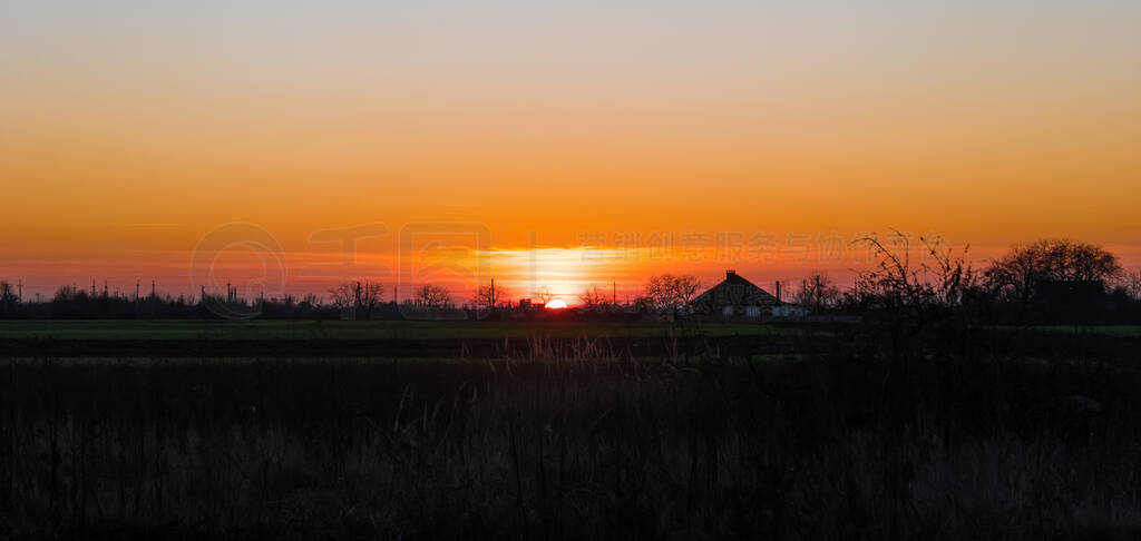 Beautiful sunset over a village. Vivid sky of golden and orange