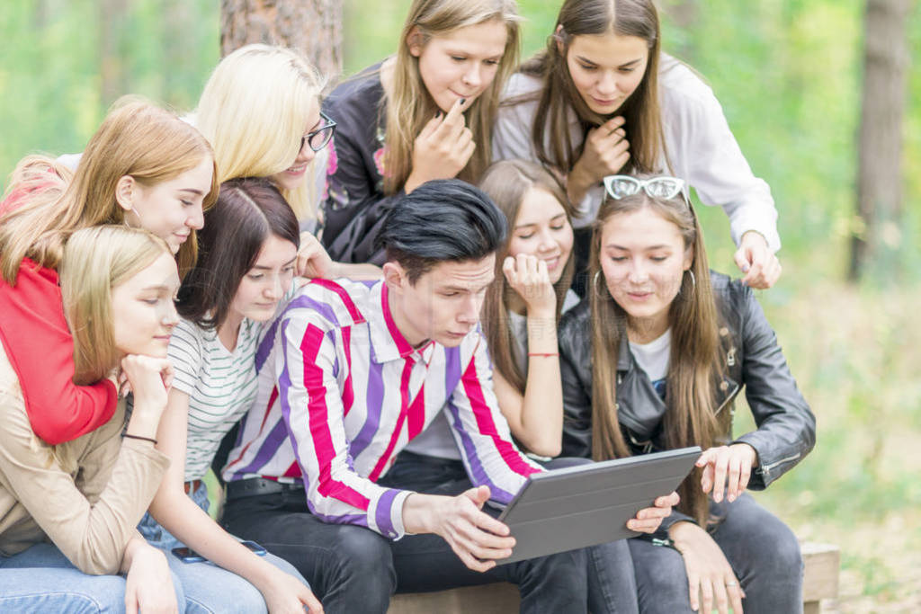 A group of teenagers 15-19 years old are looking at a tablet in