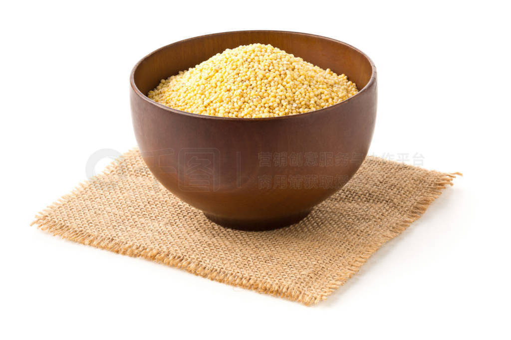 Pile of golden millet, a gluten free grain seed, in wooden bowl