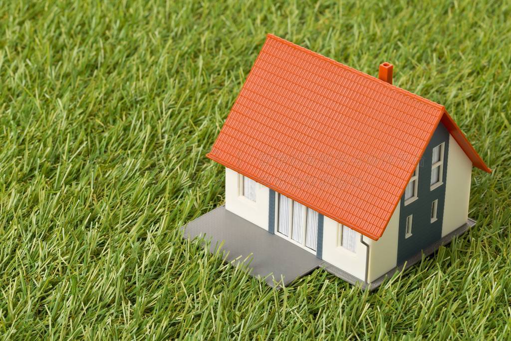 Miniature house model on green grass lawn background