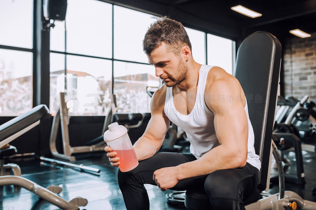 Young man holding energy drink in a bottle and taking a break