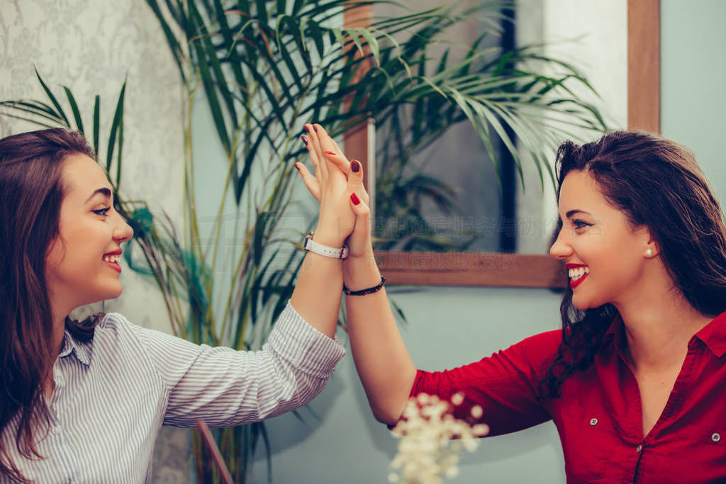 Happy female friends are giving high, celebrating success while