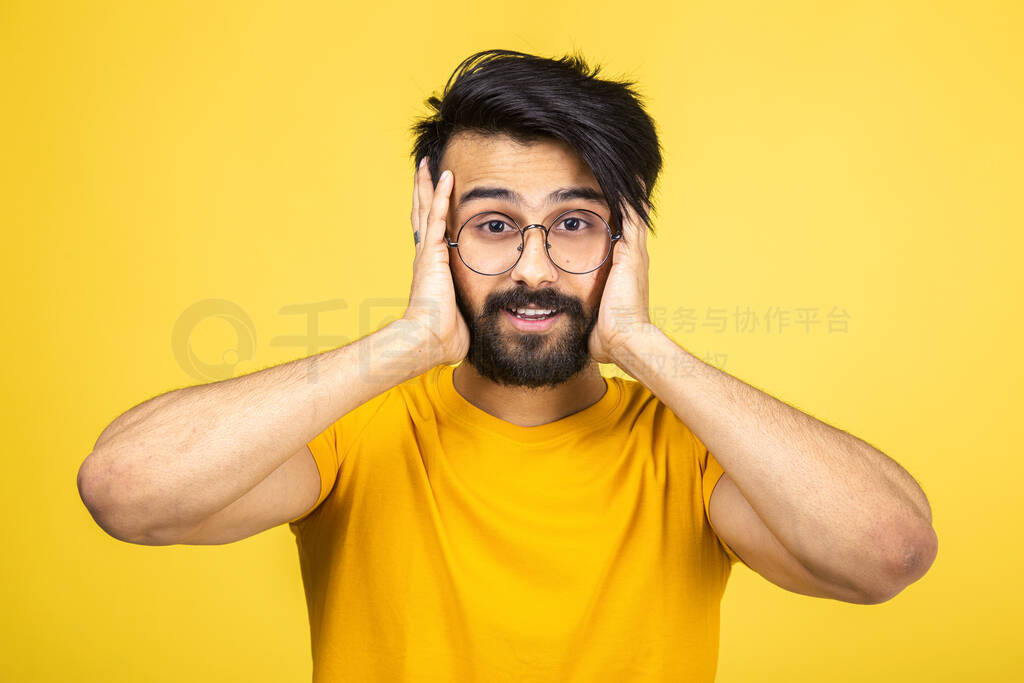 Emotional portrait of a Hindu man in a yellow T-shirt on a brigh