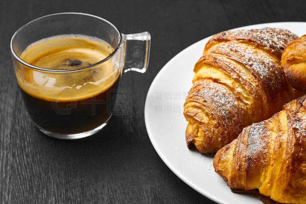 Cup of coffee and freshly baked croissants on a dark table. Serv