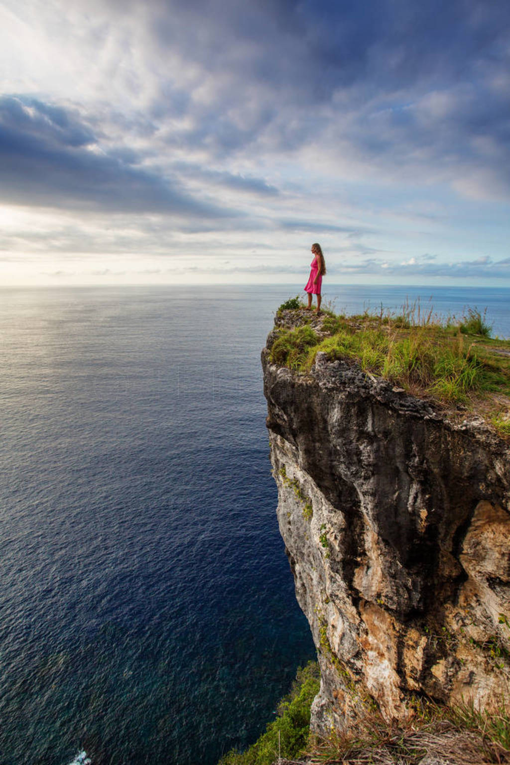 woman sitting on the edge of a cliff and looking at sunset, Nus