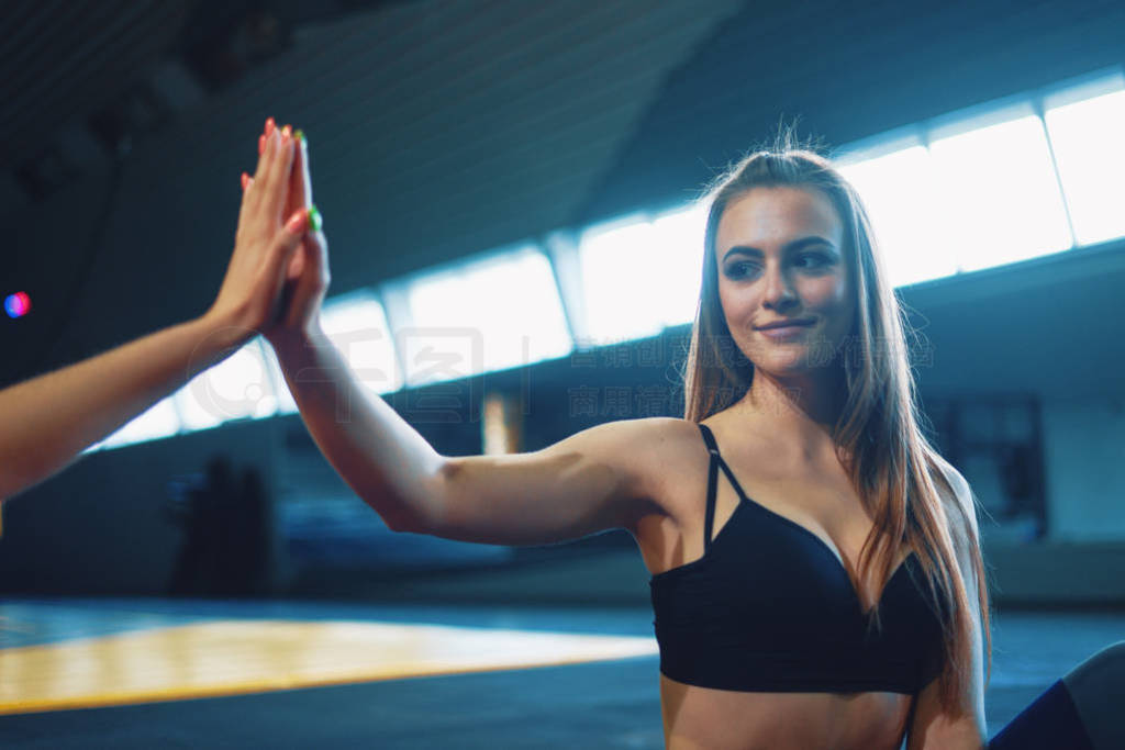 Young attractive girls giving five at sports gym background