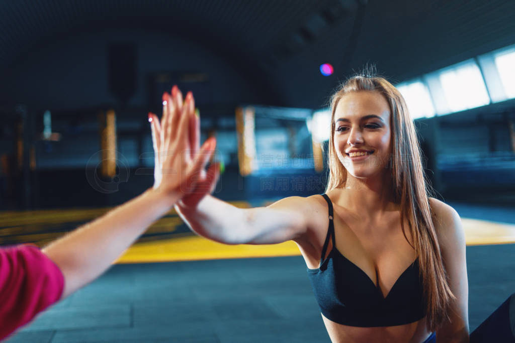 Young attractive girls giving five at sports gym background