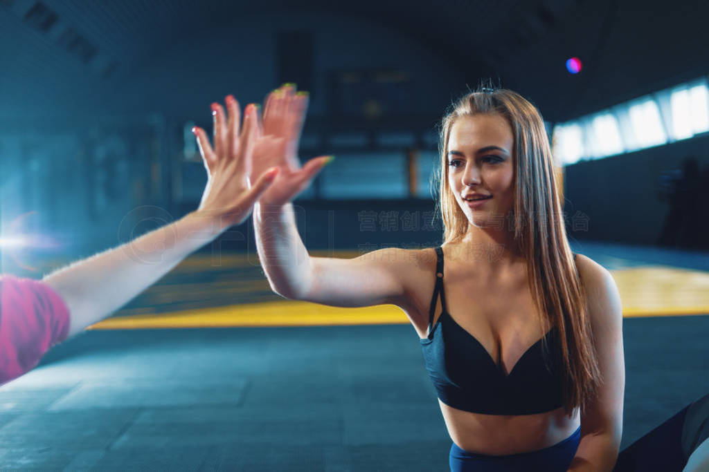 Young attractive girls giving five at sports gym background