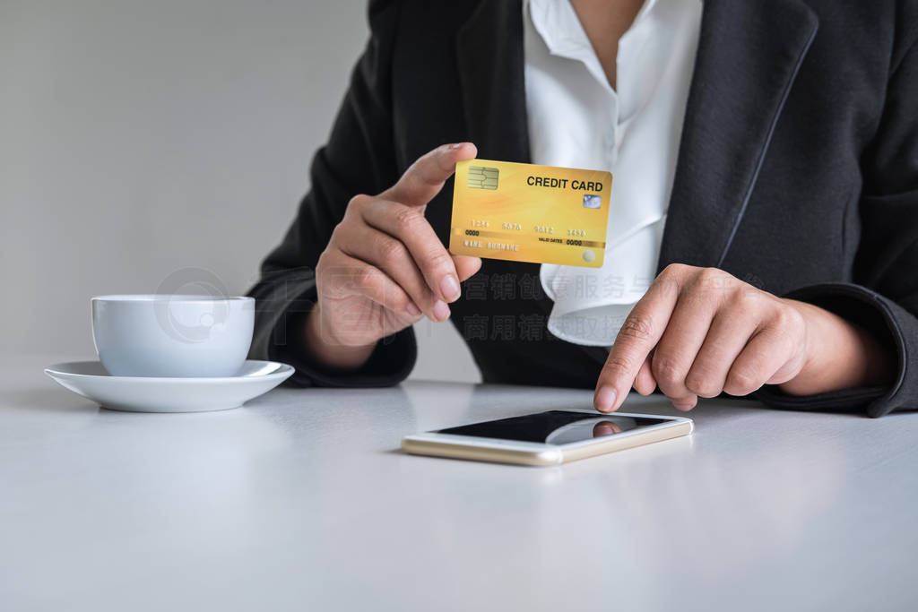 Young woman consumer holding smartphone, credit card and typing