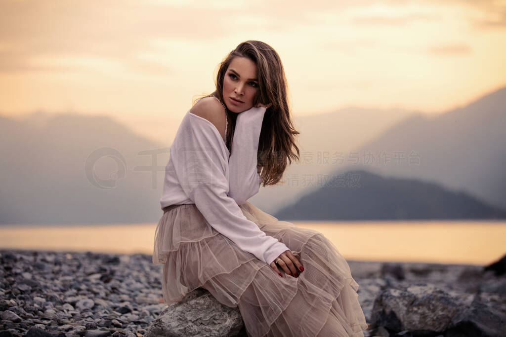 Fashionable female model in stylish outfit posing over mountain