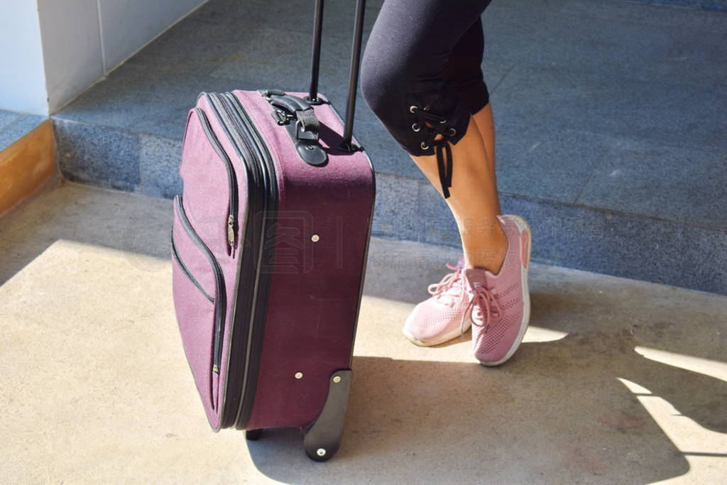 Girl with a travel suitcase. Women's legs and luggage bag.