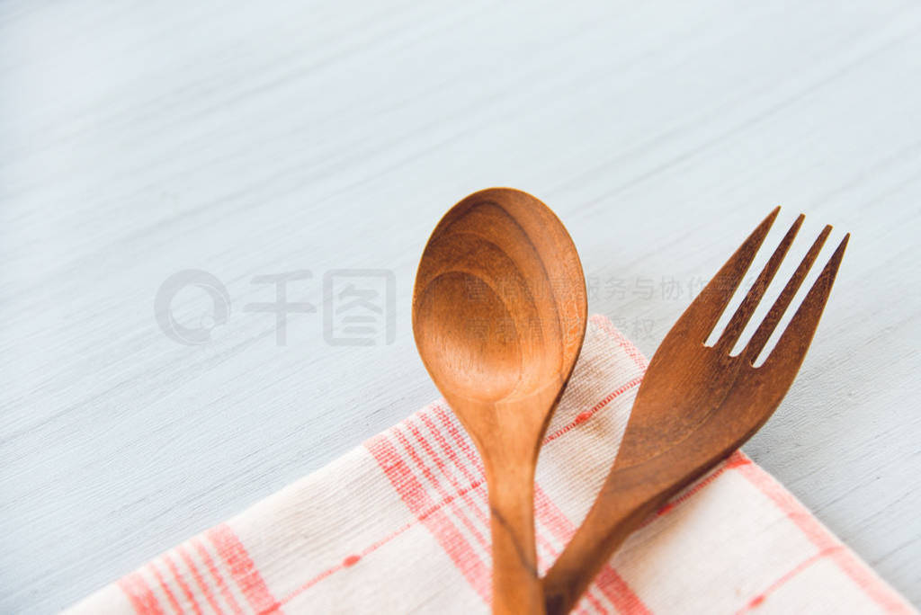 Wooden spoon and fork kitchenware set on napery on dining table