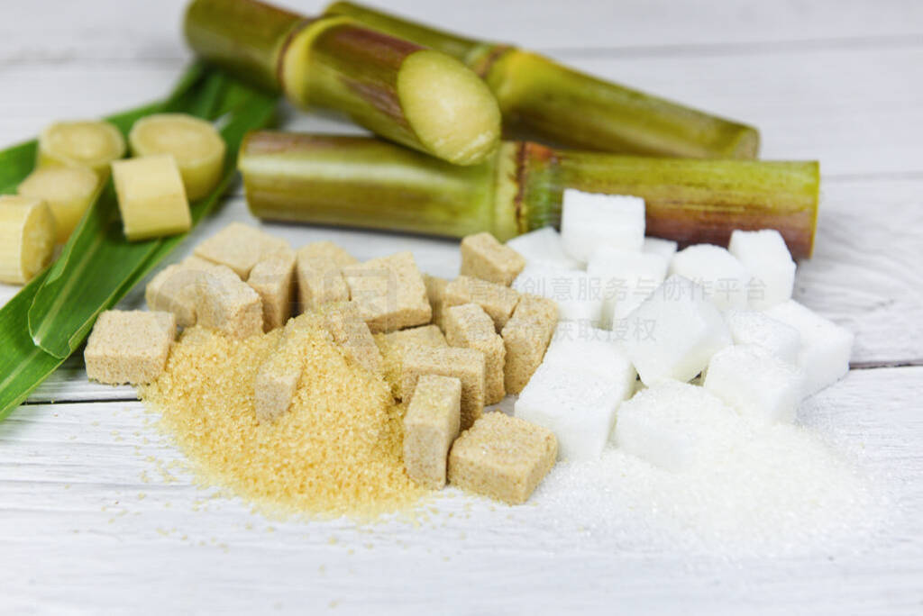 White and brown sugar cubes and sugar cane on wooden table