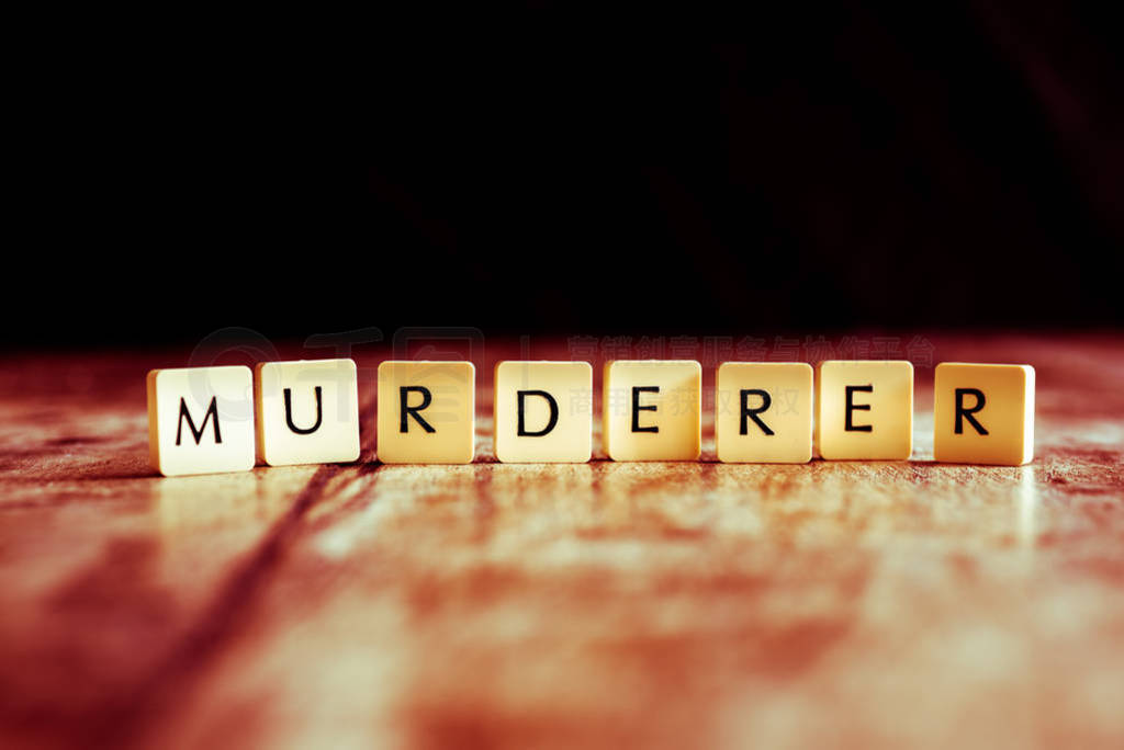 Murderer word made of tiles on dark wooden background