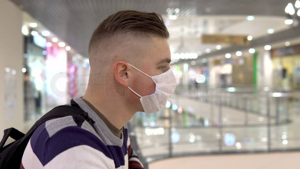 Young man in a medical mask on the second floor in a shopping ce
