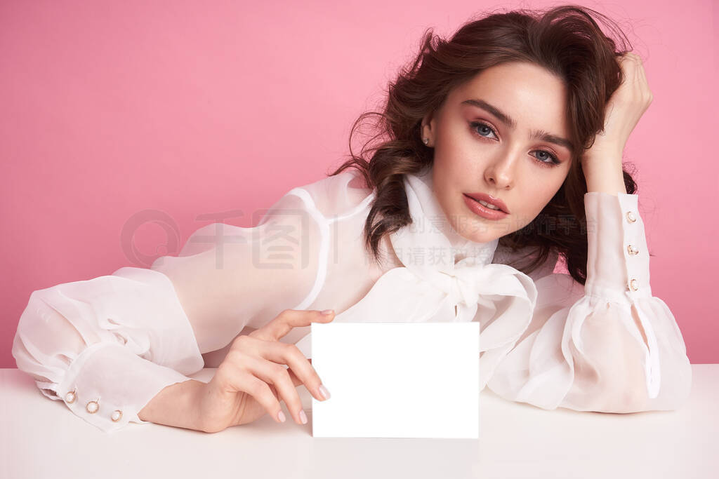 Young girl on a pink background holds an empty sheet to fill