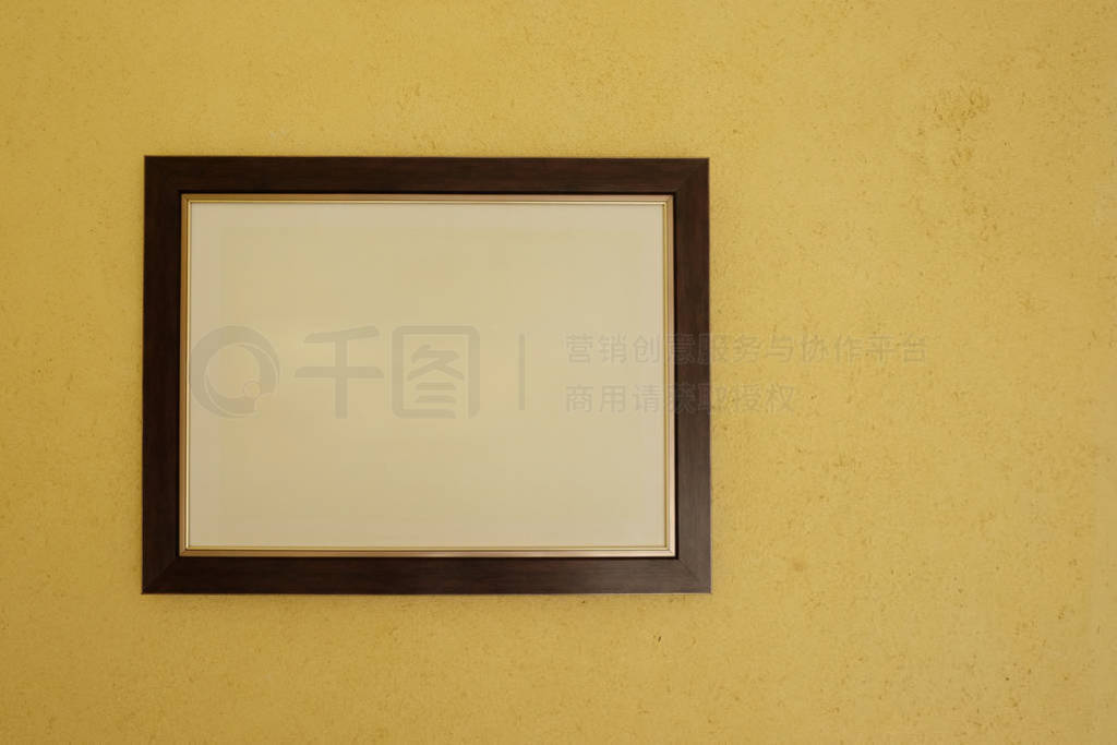 Empty picture frames on vintage yellow walls.