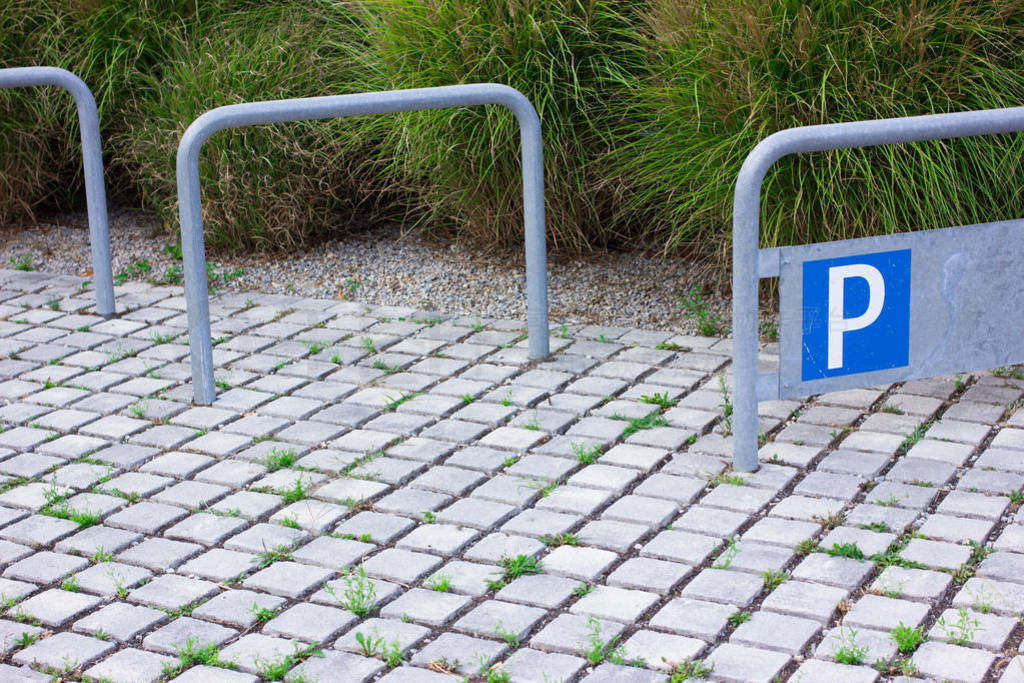Empty bike parking with blue parking sign. Metal parking frames