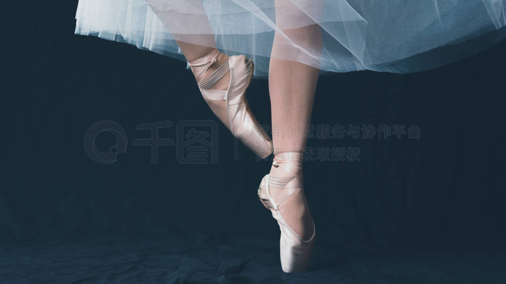 Close-up of dancing legs of ballerina wearing white pointe on a