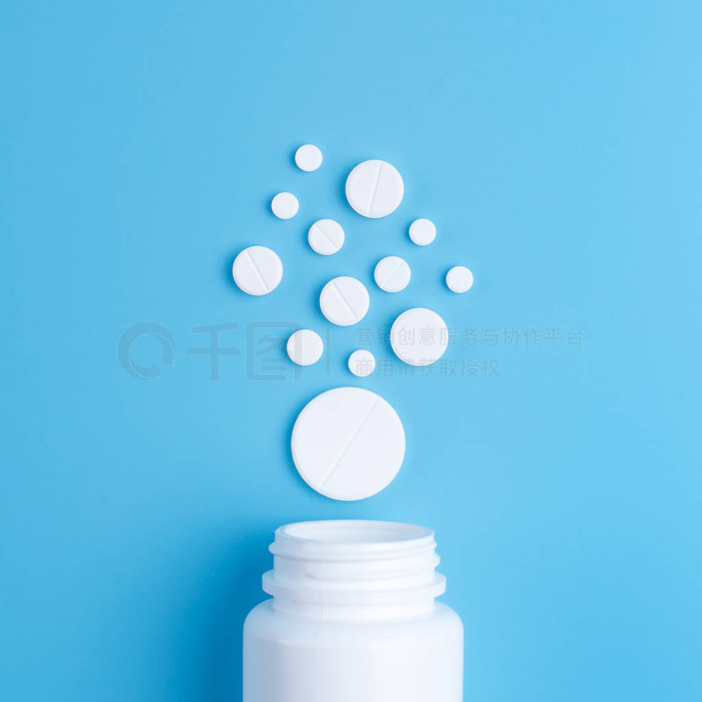 Medicine white pills or tablets drop out of the white bottle on