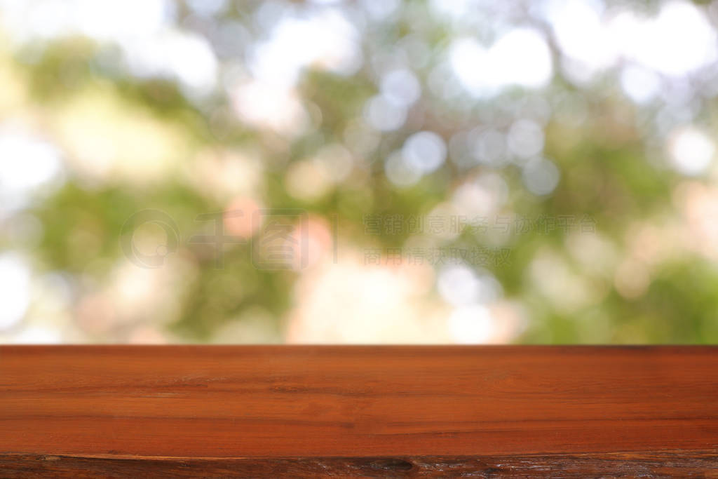 Empty wooden table in front of abstract blurred green bokeh ligh