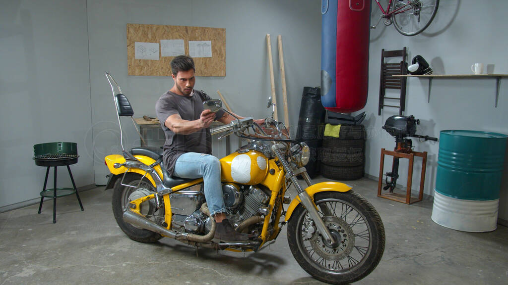 Man sits on a motorcycle and looks in its mirrors