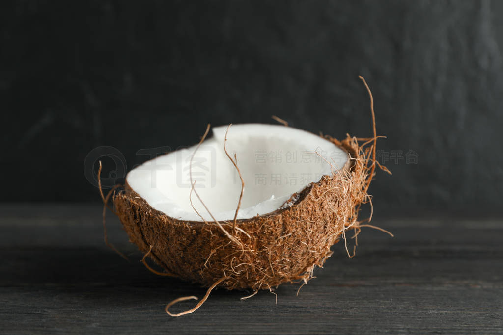 Half tropical coconut on wooden table against black background,