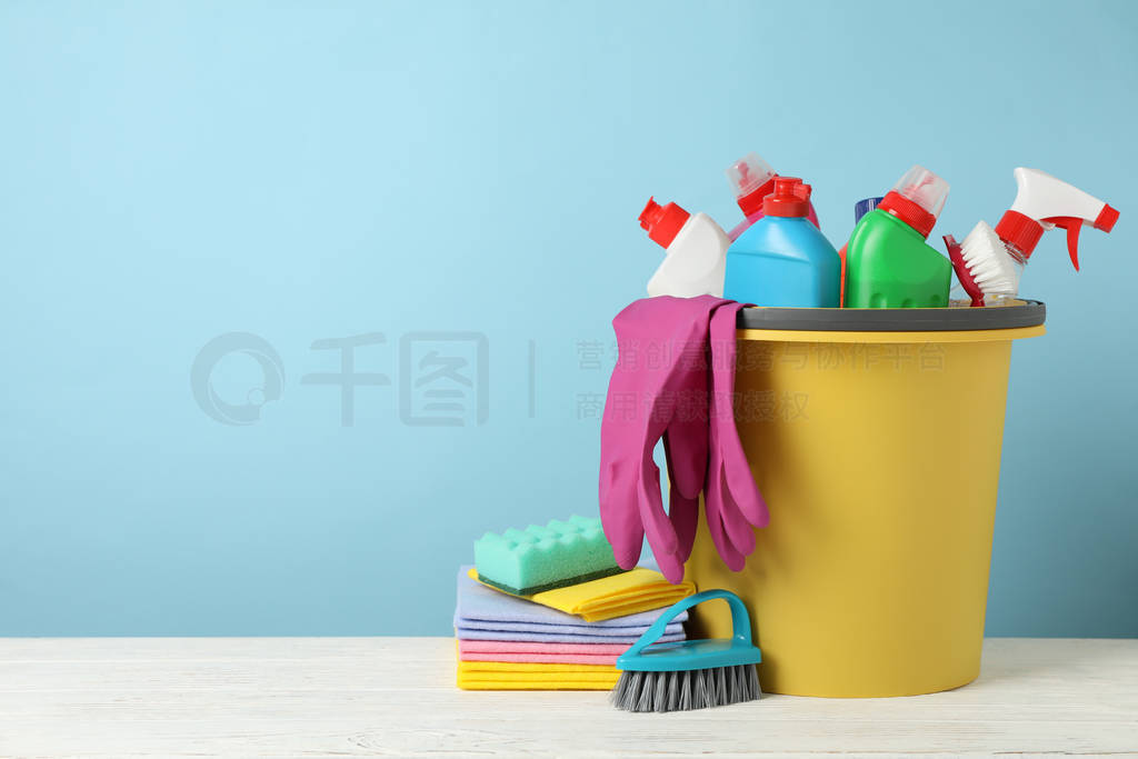 Bucket with detergent and cleaning supplies on blue background,