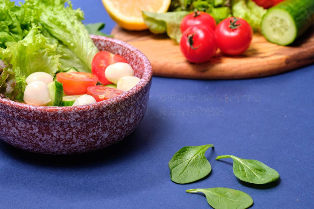 fresh vegetables and a bowl of salad with mozzarella on a blue b