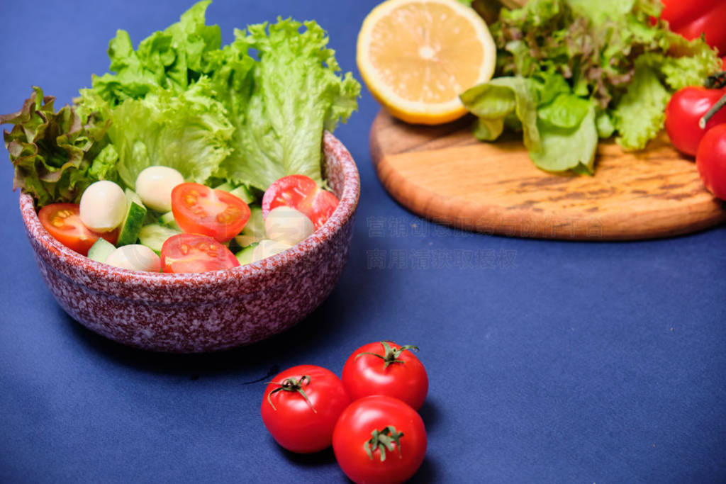 fresh vegetables and a bowl of salad with mozzarella on a blue b