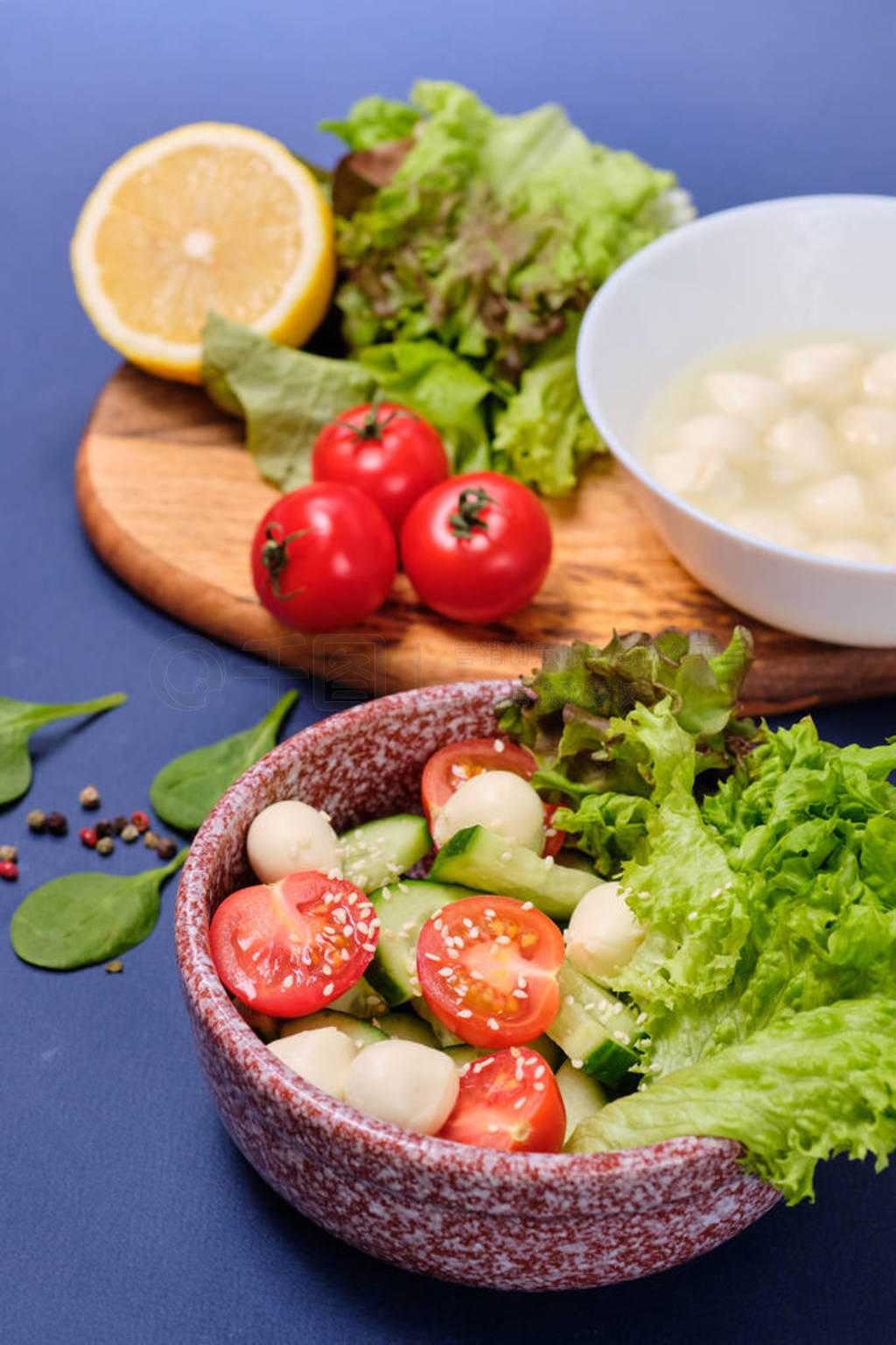 fresh vegetables and a bowl of salad with mozzarella on a blue b