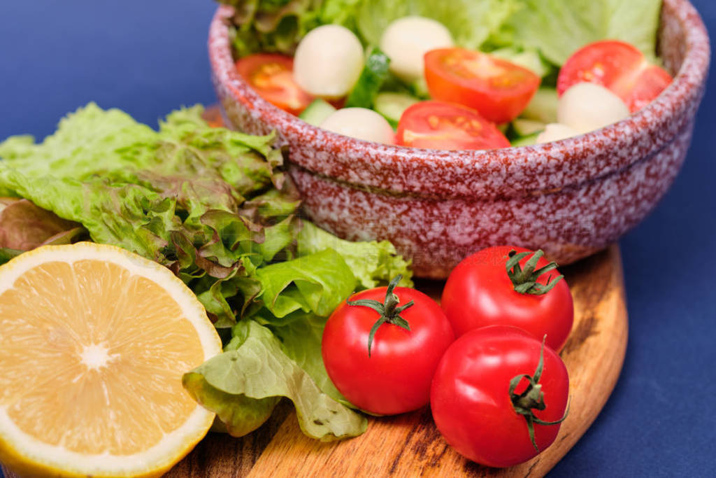 fresh vegetables and a bowl of salad with mozzarella on a blue b