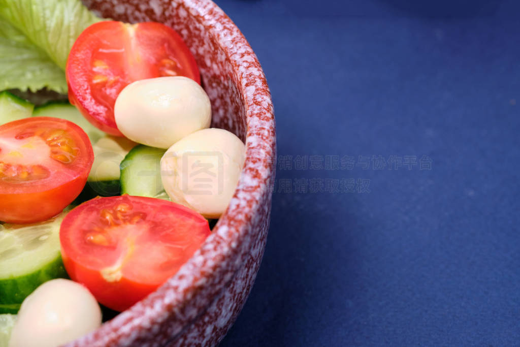 fresh vegetables and a bowl of salad with mozzarella on a blue b