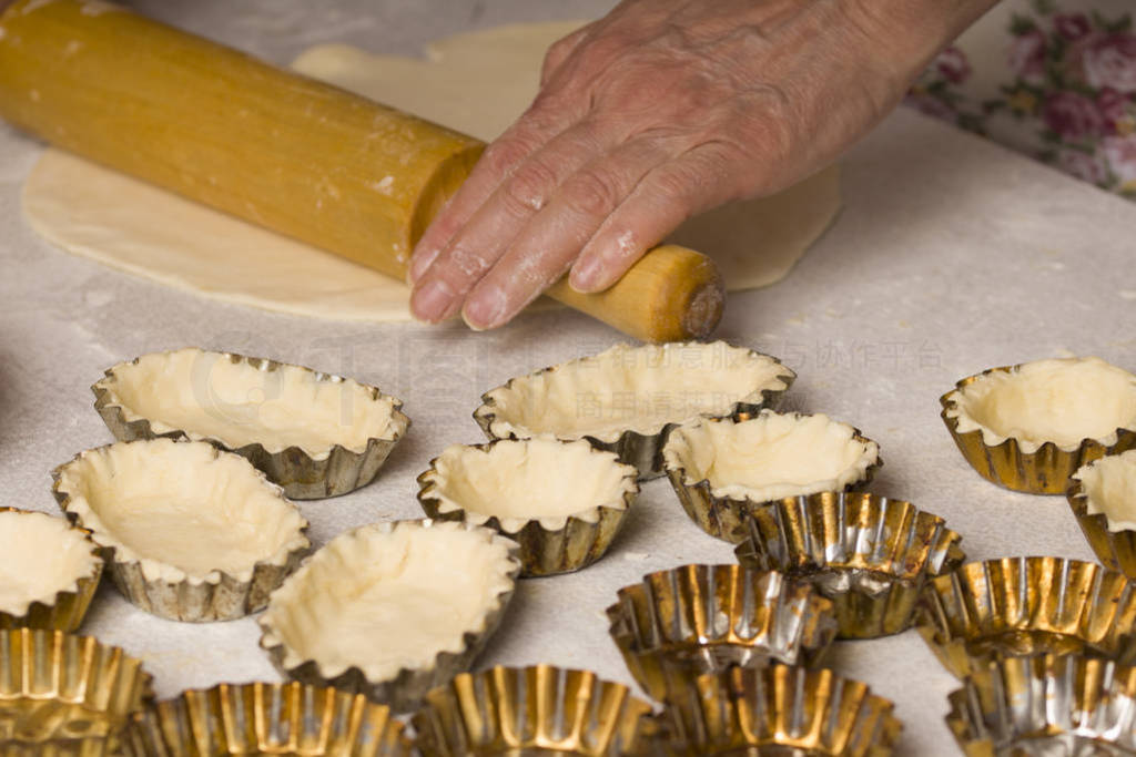 Raw dough in tartlet tins on baking tray. Uncooked pie crust in