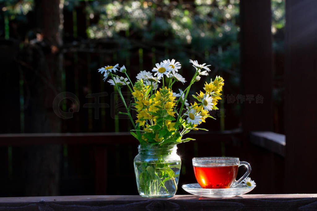 A cup of tea and a bouquet of wild flowers in the sunset light.