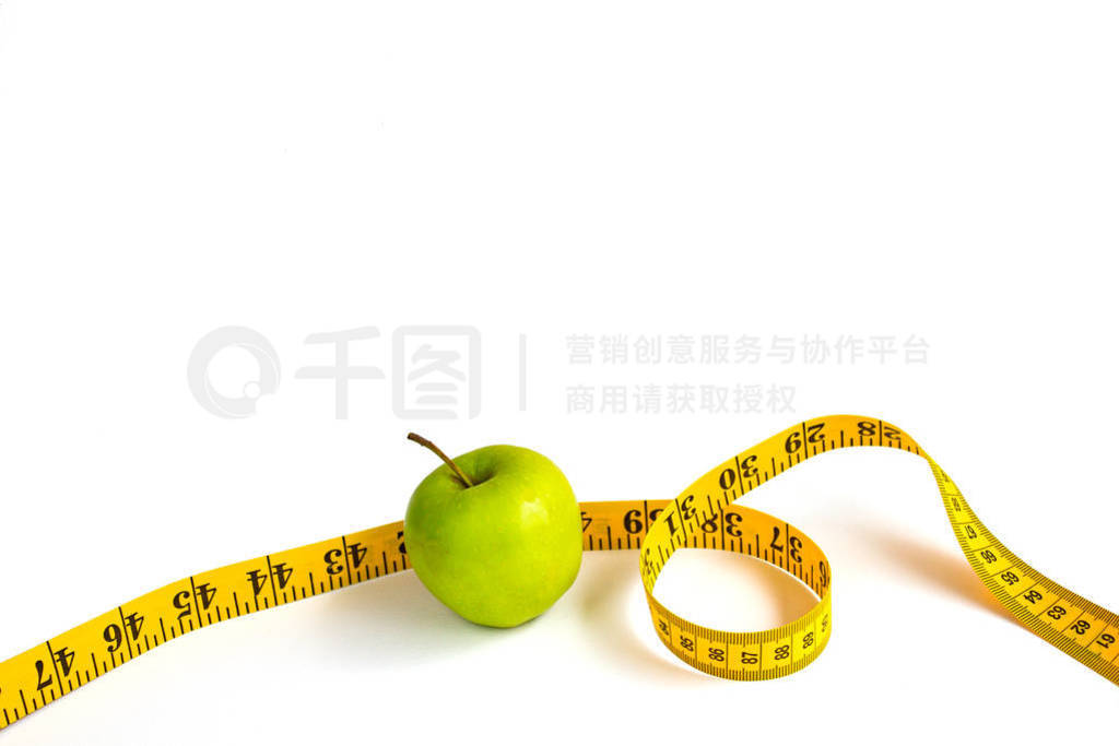 Green apple and measuring tape with centimeters and inches
