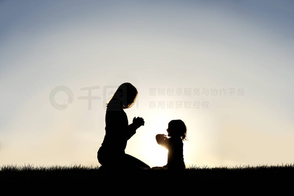 Young Mother and her Little Child are Praying Outside at Sunset