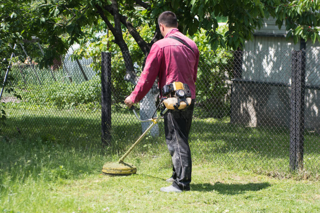 A man mows the grass on the lawn mowers. Overalls and tools.