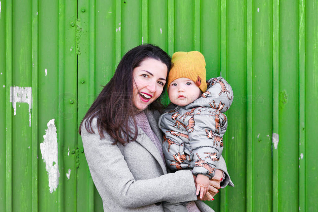 mom with a baby on a green background. wear a hat and coat. plac