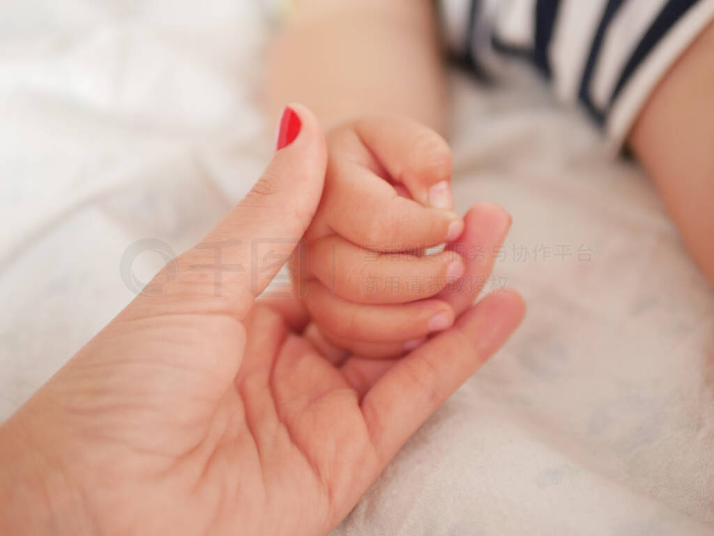 maternal hand holds her baby. Newborn children's hand in mother