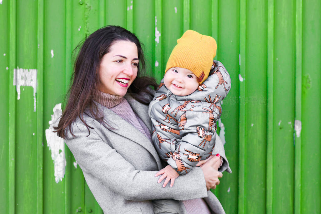 mom with a baby on a green background. wear a hat and coat. plac