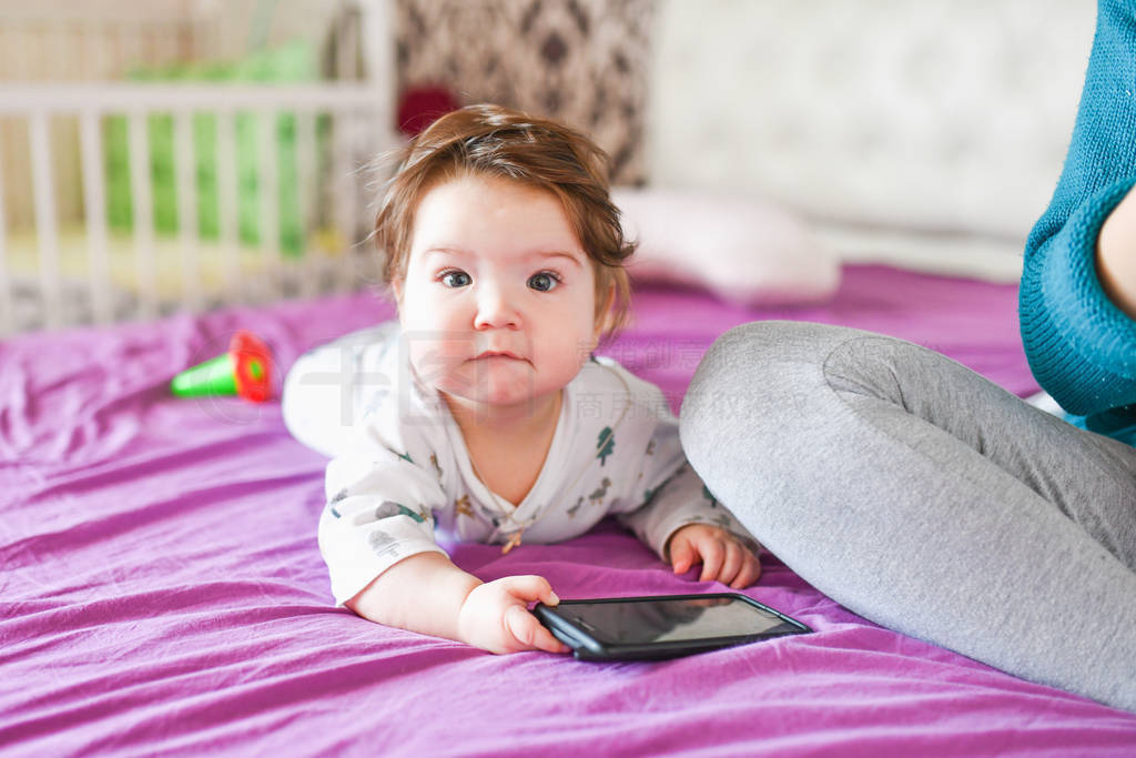 little baby with a phone. on the bed. knowledge of mobile device