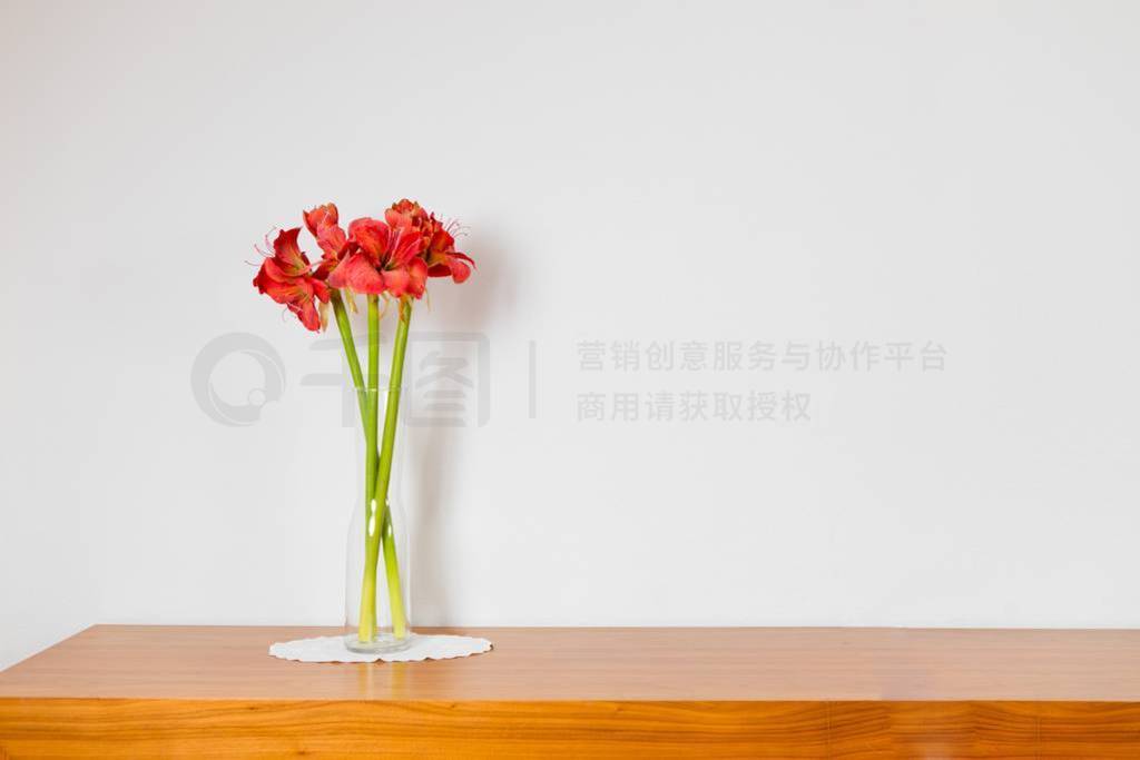 Empty brown wooden commode with three flowers on tablecloth. Red