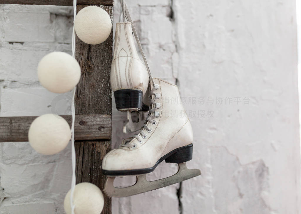 Figure skates and Christmas garland lights on old white brick ru