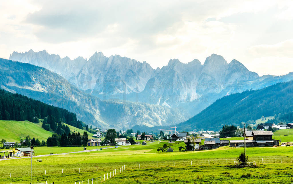 View on Alps mountains with green fields and cloudy sky. Gosau,