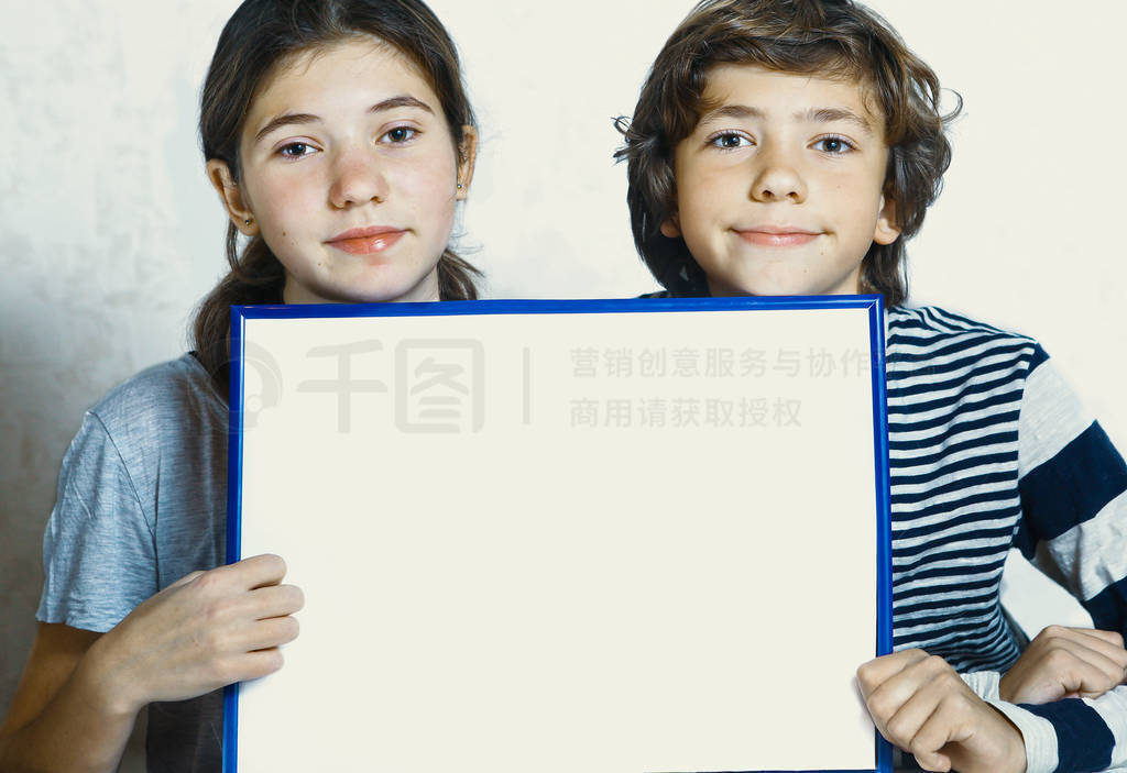 two kids boy and girl hold blank paper sheet in blue frame with