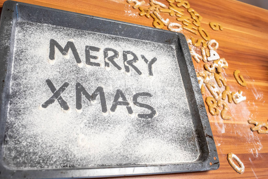 the words Merry Xmas is written on a baking tray sprinkled with
