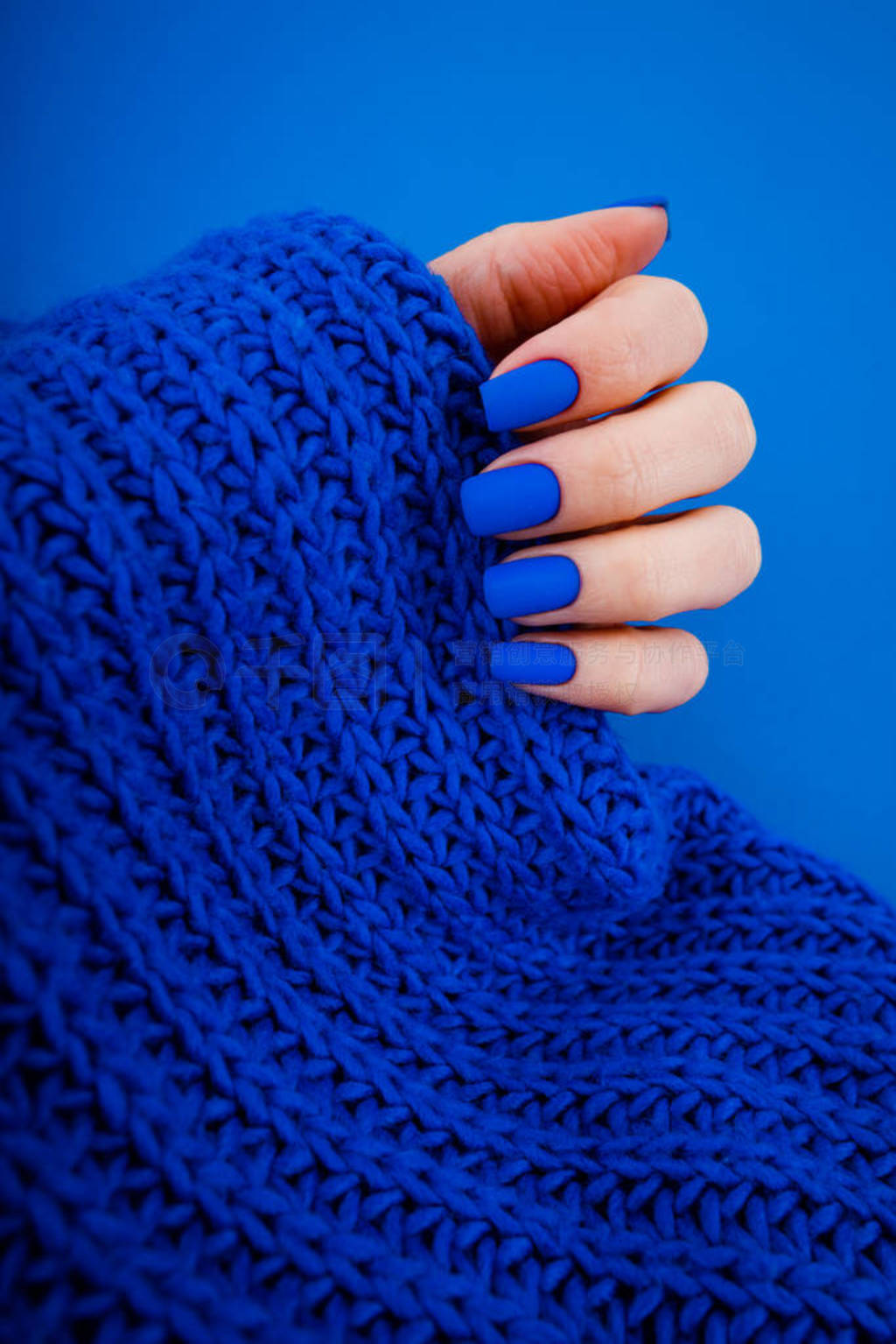Blue matte manicure on a blue background with round blue glasses
