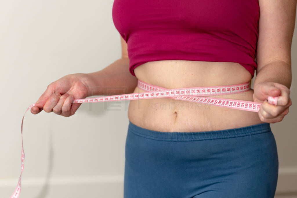 Closeup of woman pinching belly fat. Young slim woman in blue sh